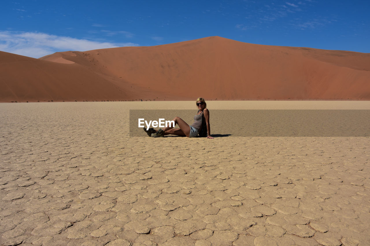 MAN SITTING ON SAND IN DESERT