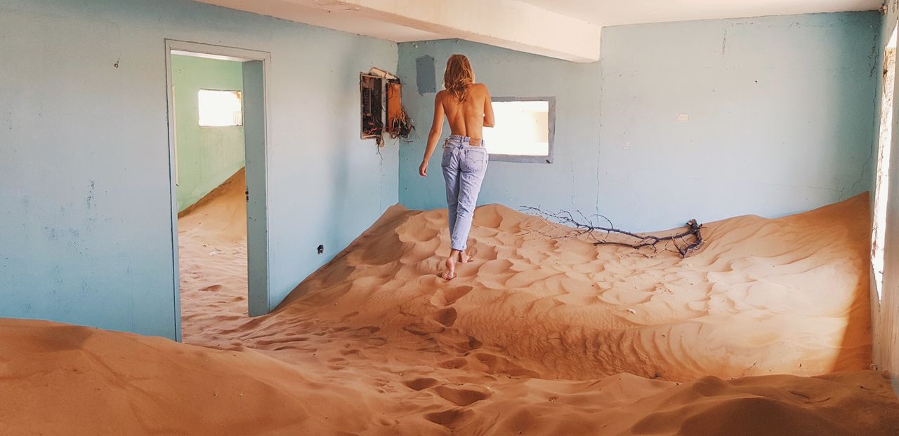 WOMAN STANDING ON BED IN SAND
