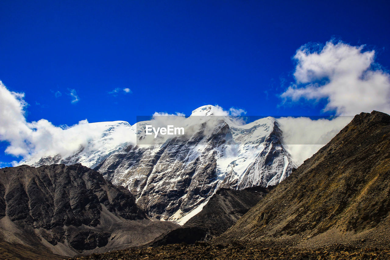 Panoramic view of snowcapped mountains against blue sky