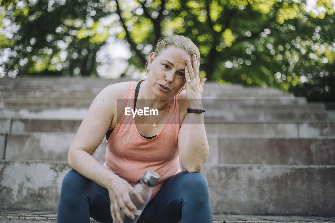 Low angle portrait of tired woman with head in hand sitting on steps