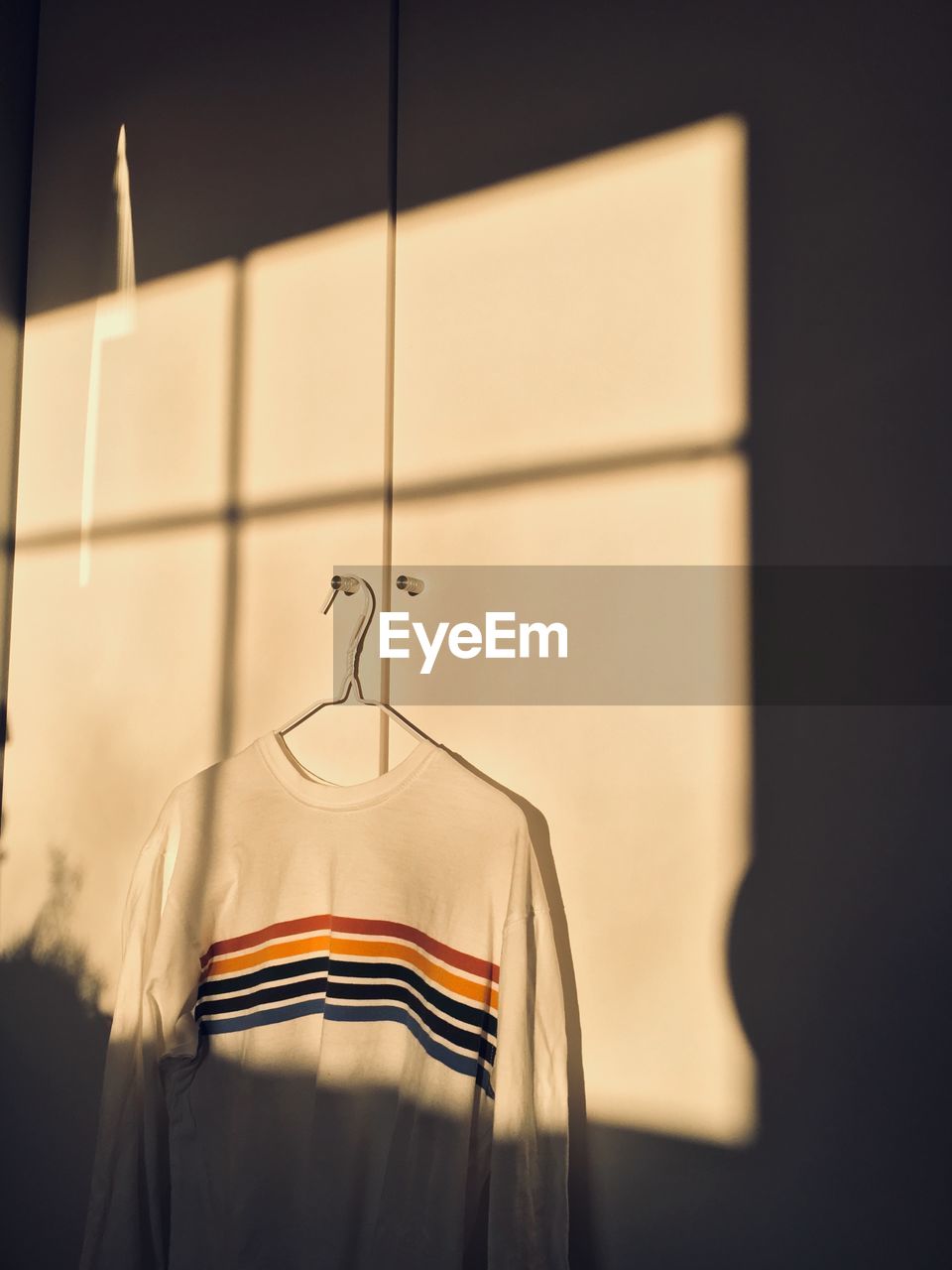 Close-up of rainbow sweater hanging on wall at home