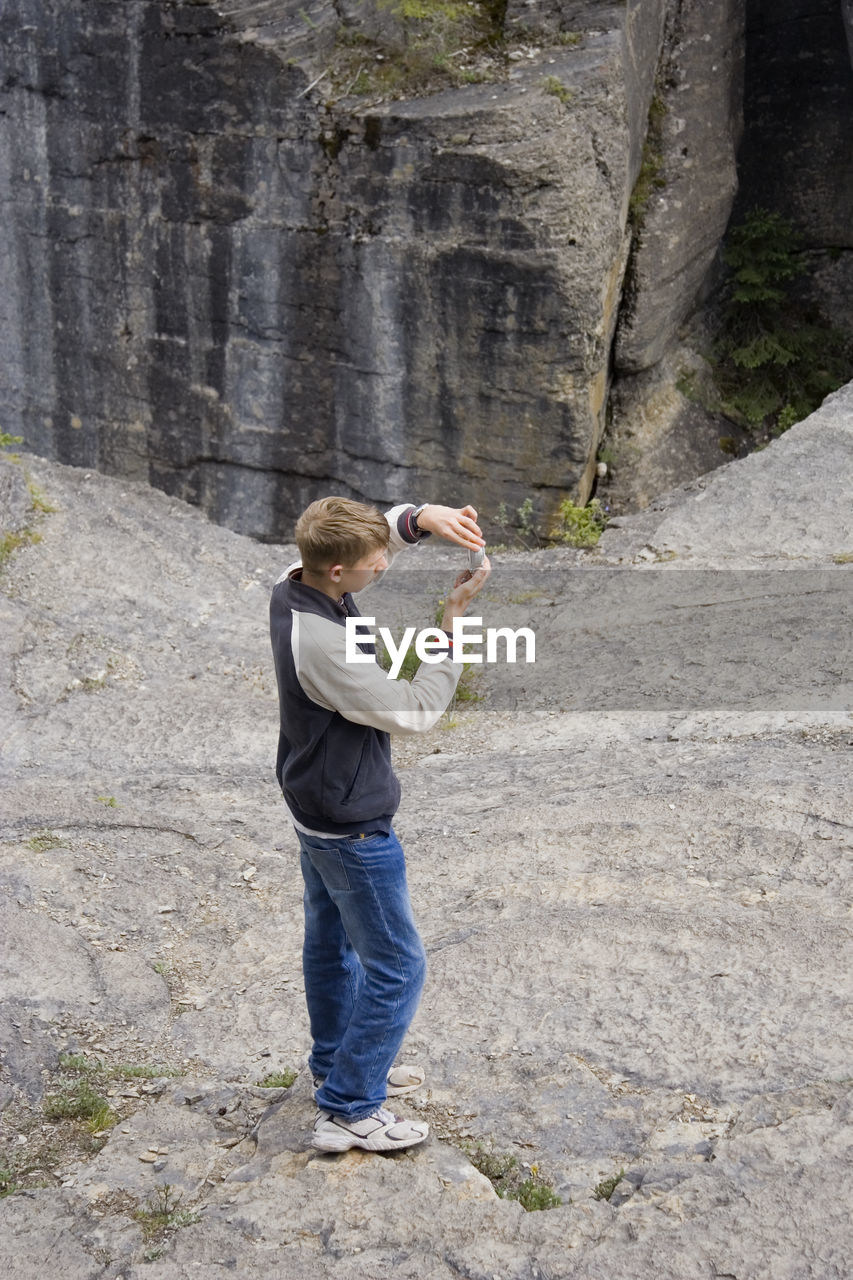 High angle view of man using phone while standing on mountain