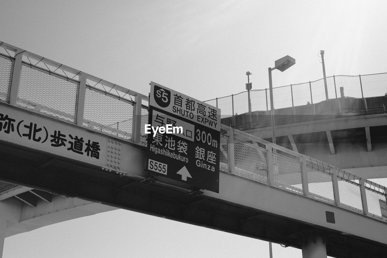 LOW ANGLE VIEW OF INFORMATION SIGN AGAINST BRIDGE