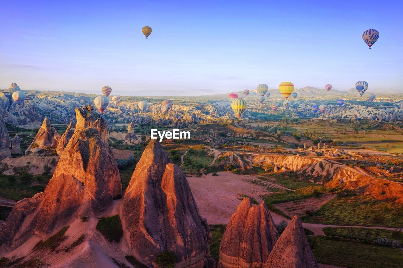 Hot air balloons flying over rock formations at cappadocia