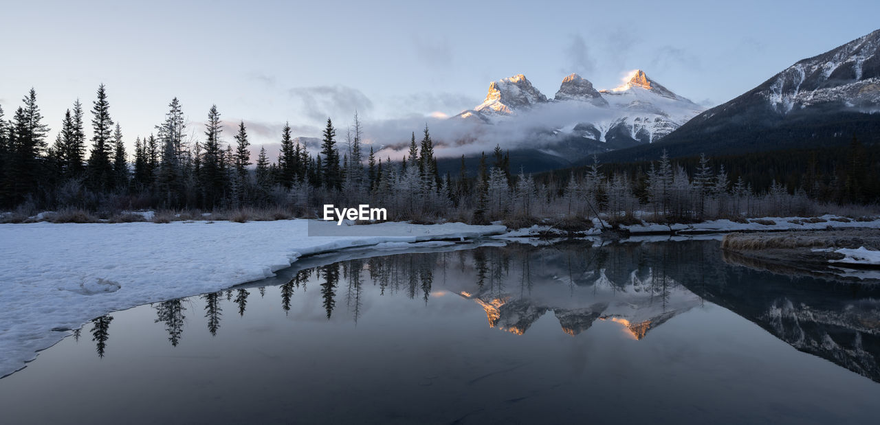 Panoramic winter sunrise shot from canadian rockies,three sisters mountain, canmore, alberta, canada