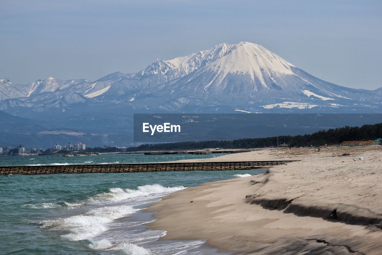 Scenic view of snowcapped mountains by sea against sky