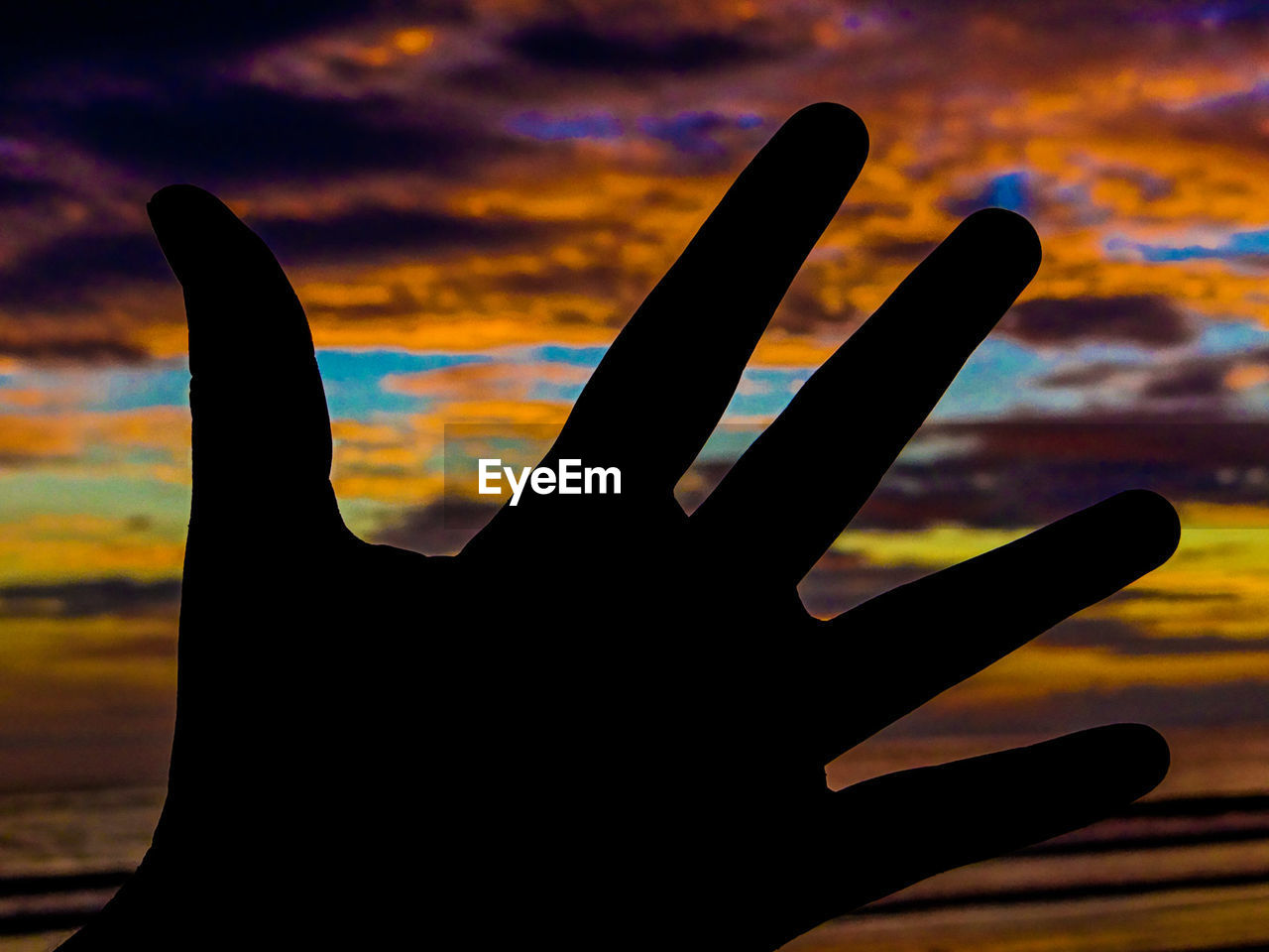 CLOSE-UP OF SILHOUETTE HAND AGAINST SKY
