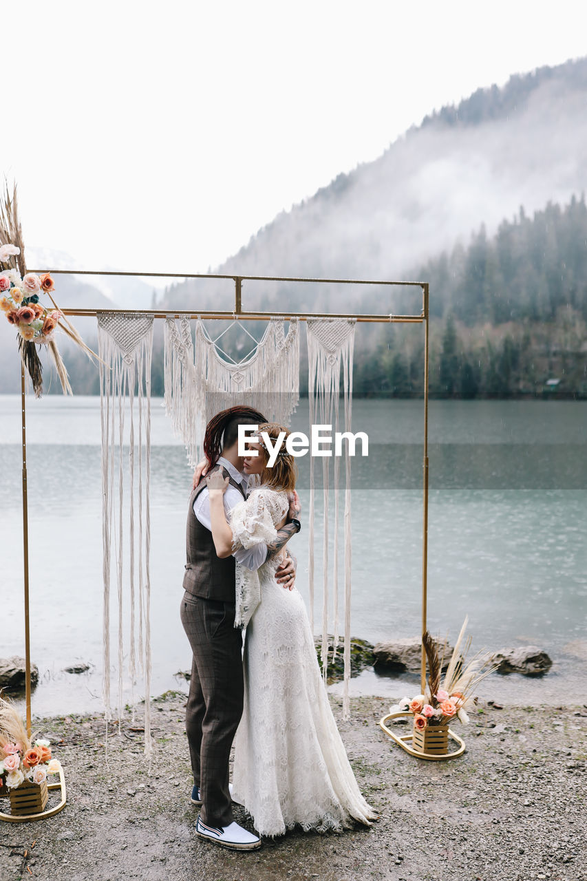 A happy couple in love and married embrace in nature by the lake and the misty mountains