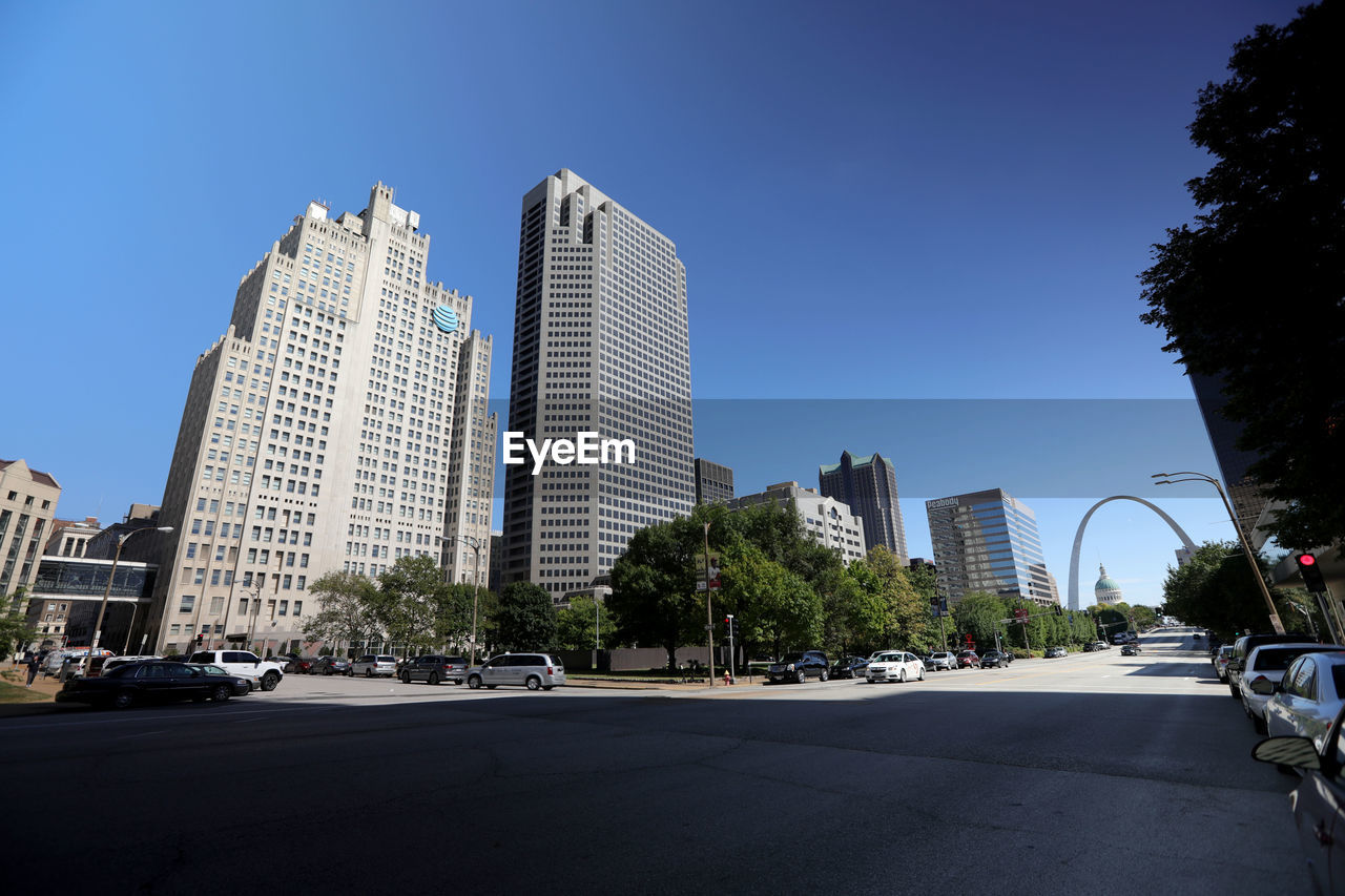 CITY STREET BY MODERN BUILDINGS AGAINST SKY