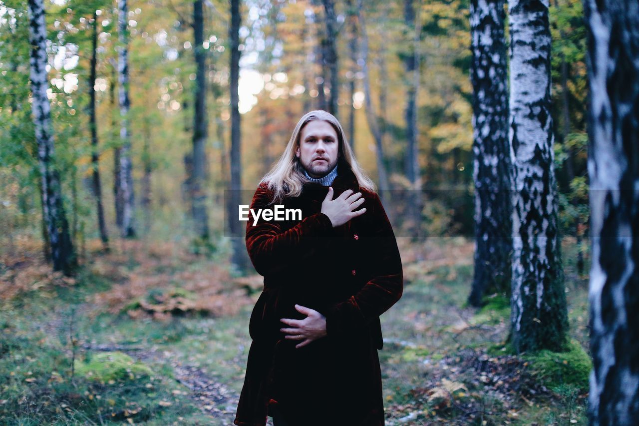 Man wearing coat standing in forest