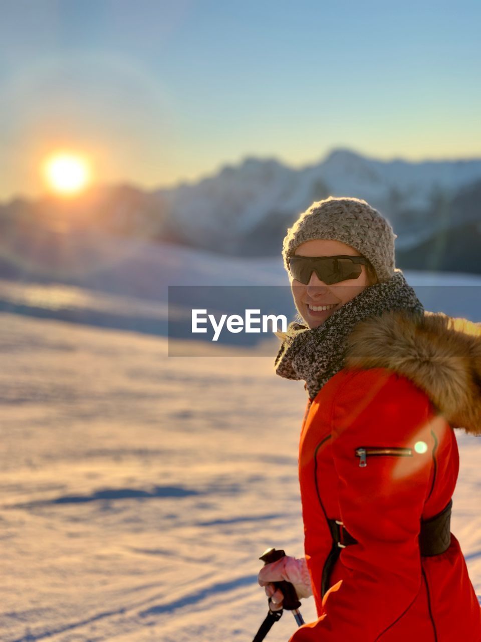 Portrait of woman skiing on snow against sky during sunset