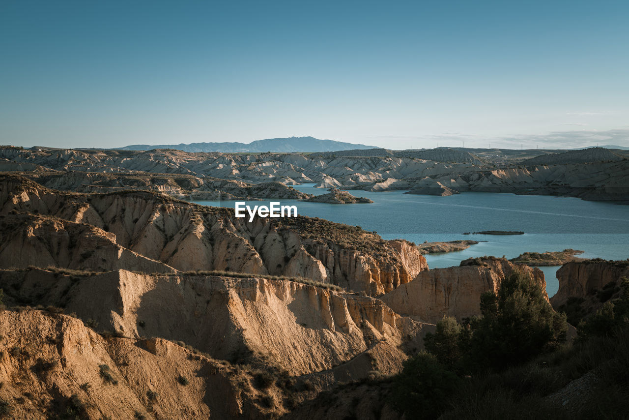 Scenic view of sea and mountains against clear sky