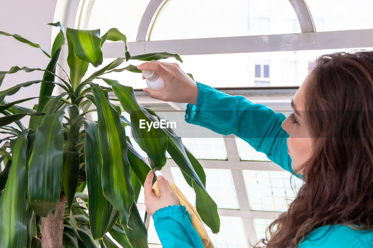 FULL LENGTH PORTRAIT OF GIRL HOLDING PLANTS