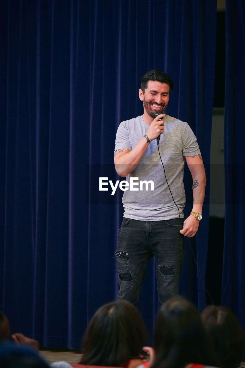 Smiling man choir singing into microphone in auditorium