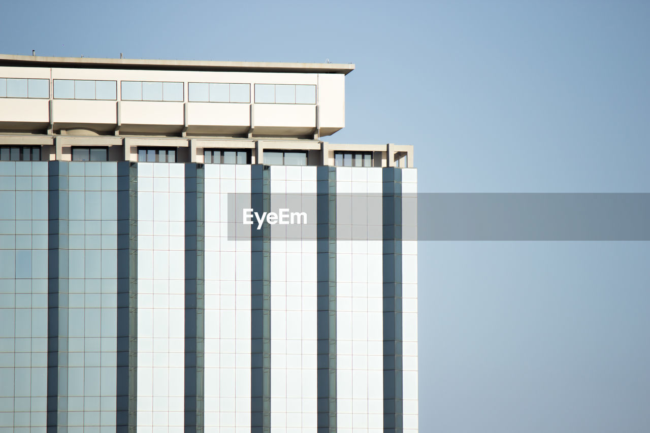 LOW ANGLE VIEW OF MODERN BUILDING AGAINST CLEAR BLUE SKY