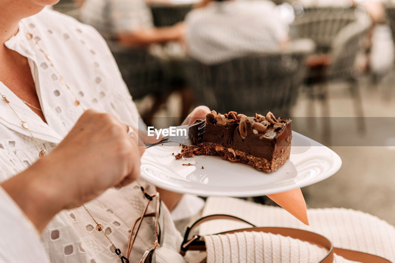 Close-up photo of woman eating delicious cake in cafe