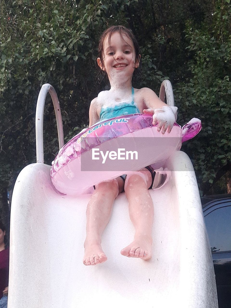 PORTRAIT OF A SMILING GIRL SITTING ON PINK FACE