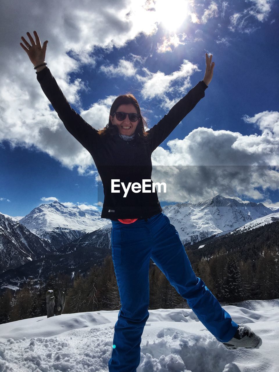 FULL LENGTH PORTRAIT OF YOUNG WOMAN STANDING ON SNOW COVERED MOUNTAIN