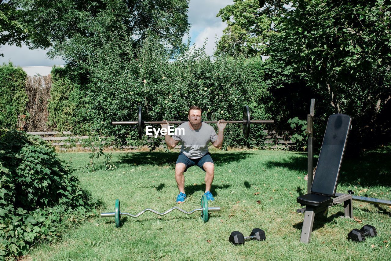 Man working out at home in the garden with his home gym equipment