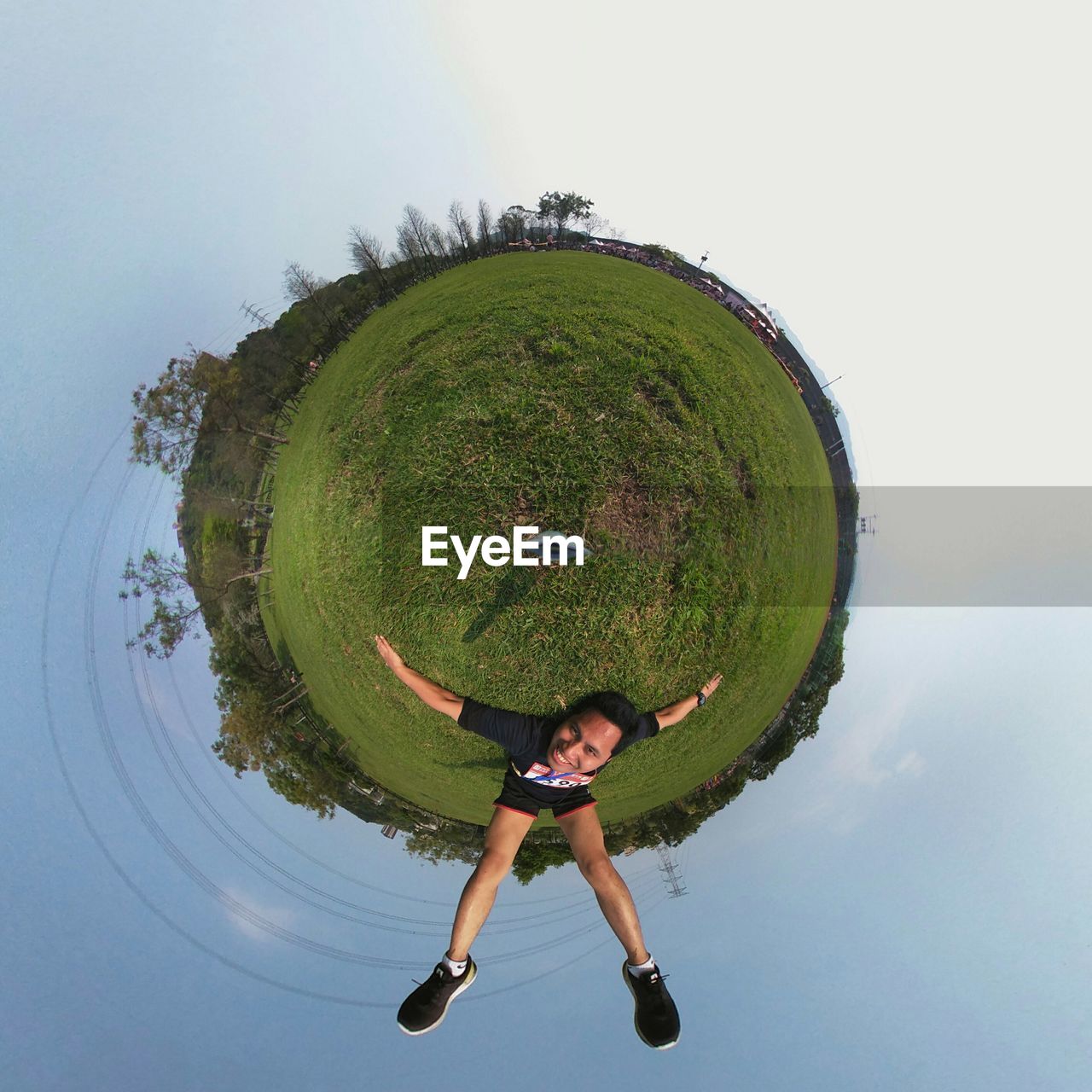 Little planet effect of man lying on field against sky