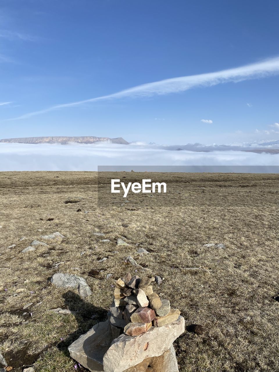 STACK OF ROCKS ON FIELD AGAINST SKY