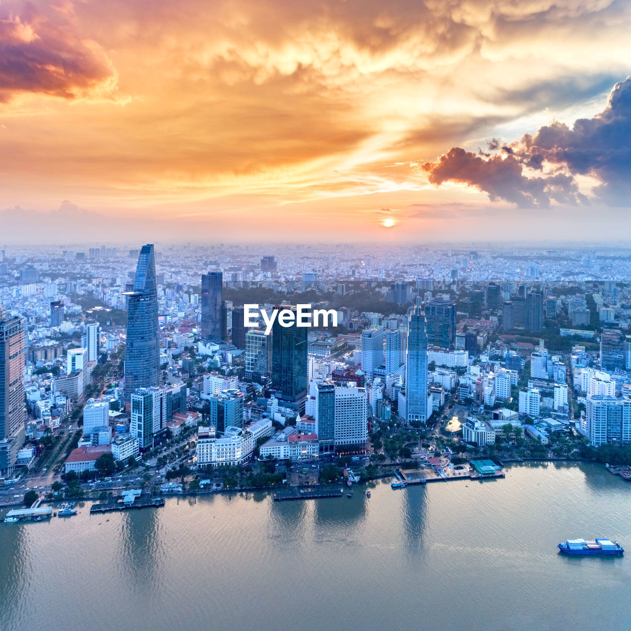 Aerial view of city by river against cloudy sky during sunset