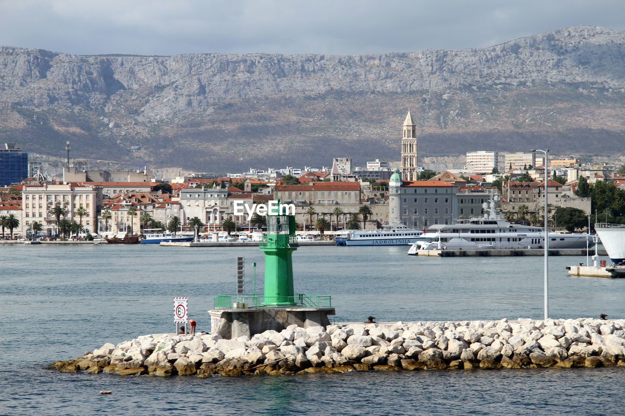 Sailboats in sea against buildings in city