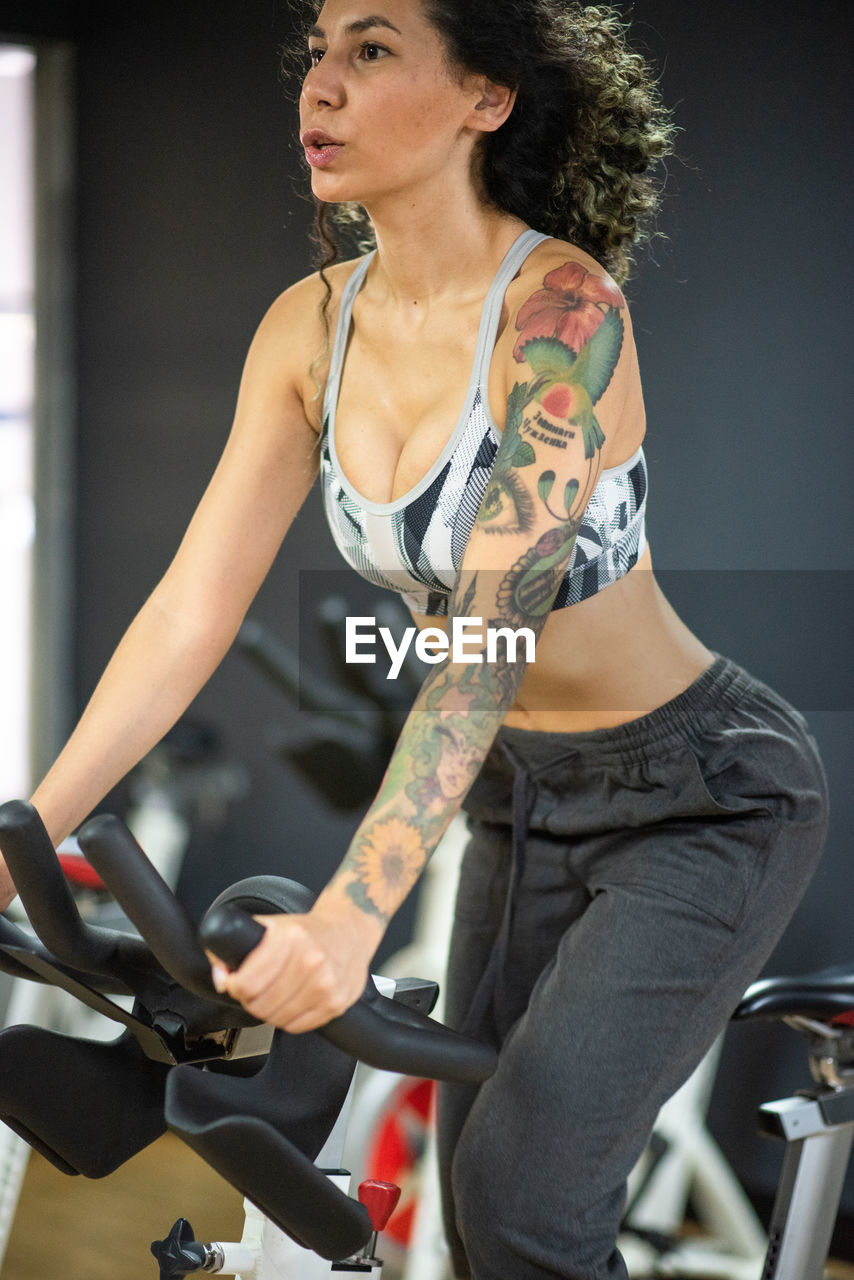 Young woman on bicycle at the gym