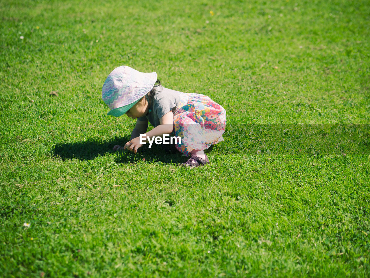 Side view of girl kneeling on grassy field