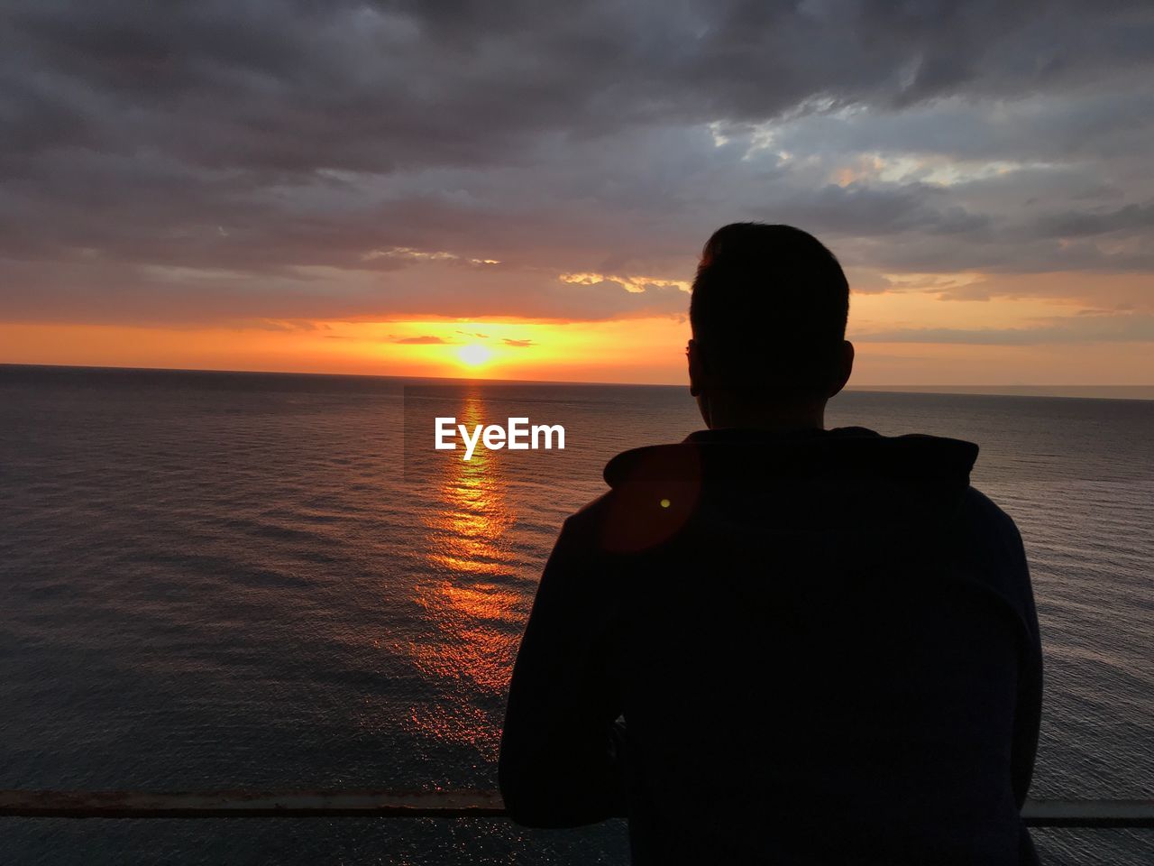 SILHOUETTE MAN LOOKING AT SEA DURING SUNSET