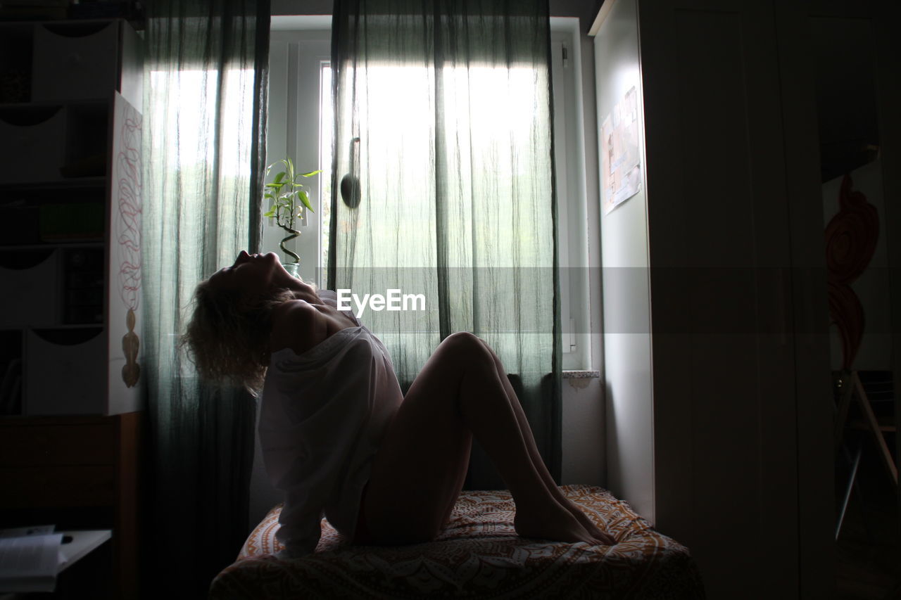 FULL LENGTH OF WOMAN SITTING AT HOME