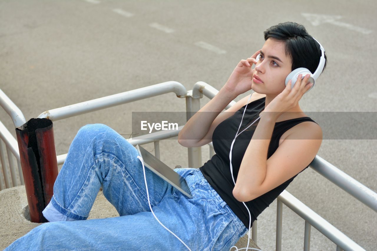 WOMAN SITTING ON RAILING