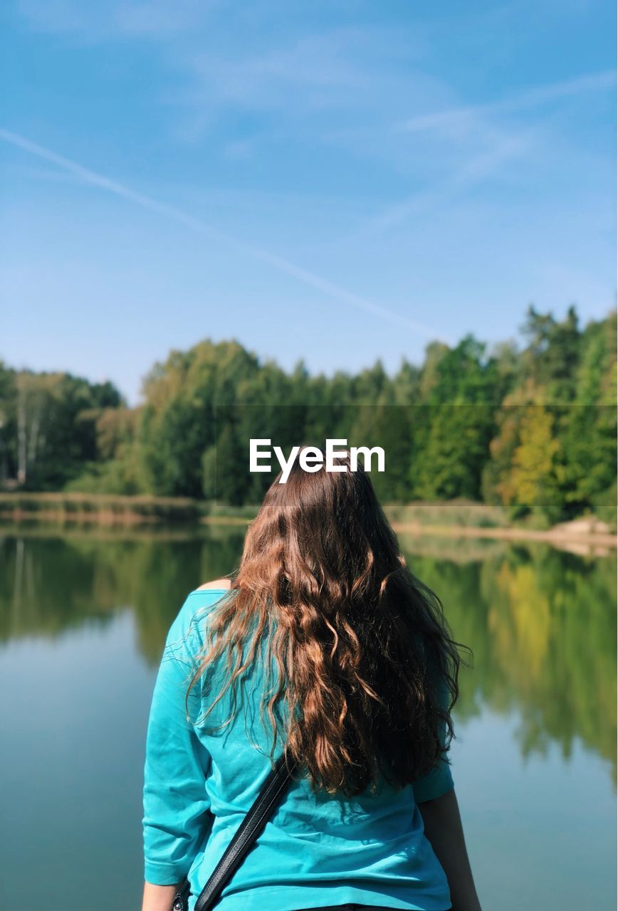 Rear view of woman looking at lake against sky