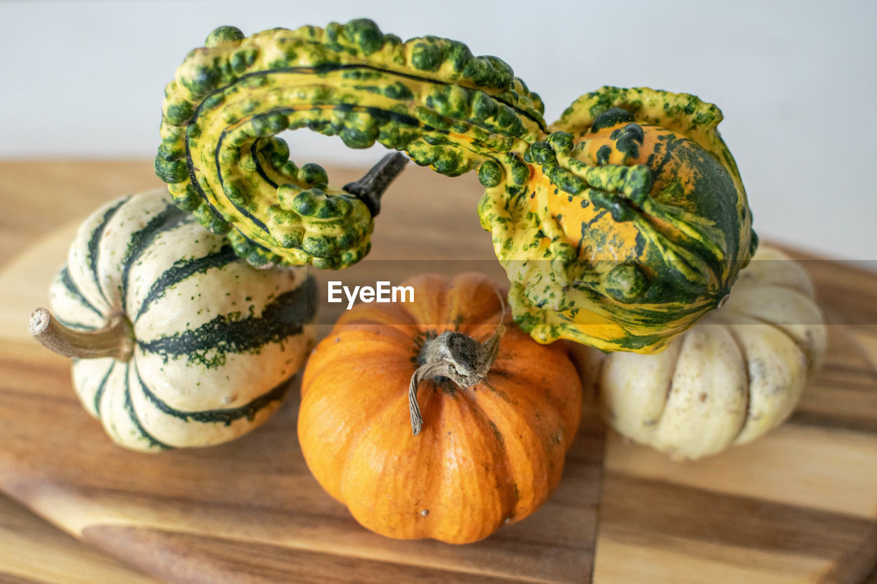 A selection of mini pumpkins balancing on top of each other on a wooden chopping board