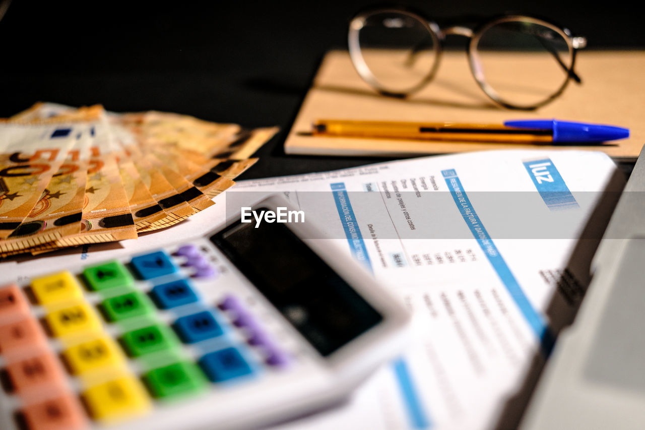 Close up view of a electric bill usage. euro cash money, glasses, pen, calculator and a laptop 