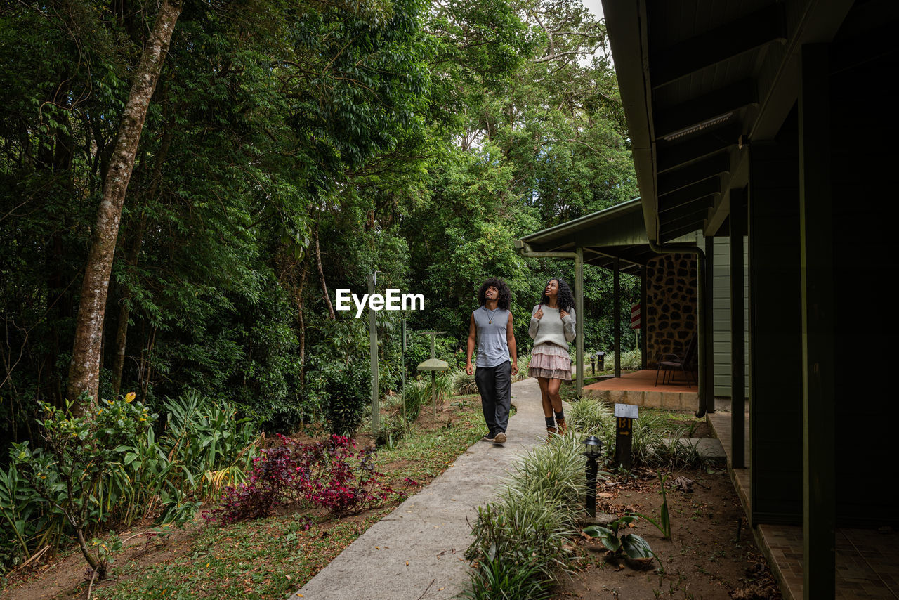 Smiling ethnic couple of travelers on footpath while looking up in village of monte verde in costa rica