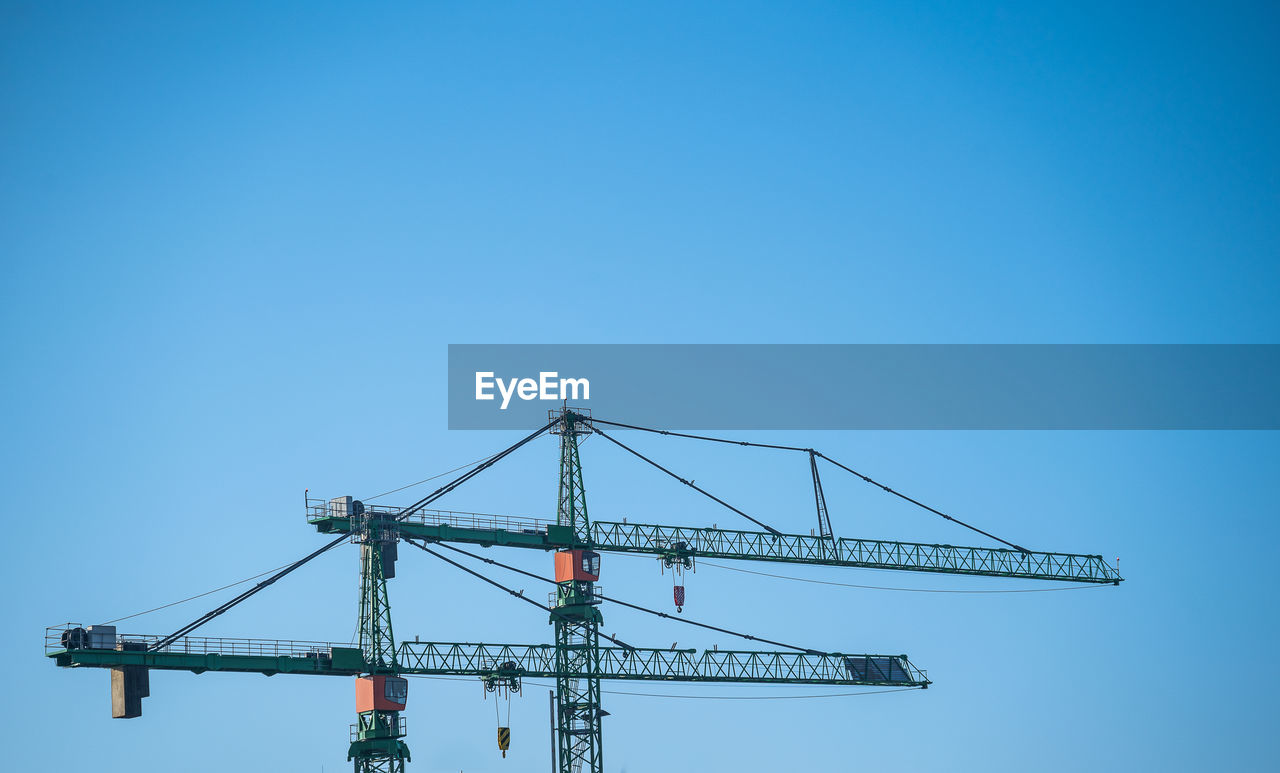 Low angle view of crane against clear blue sky