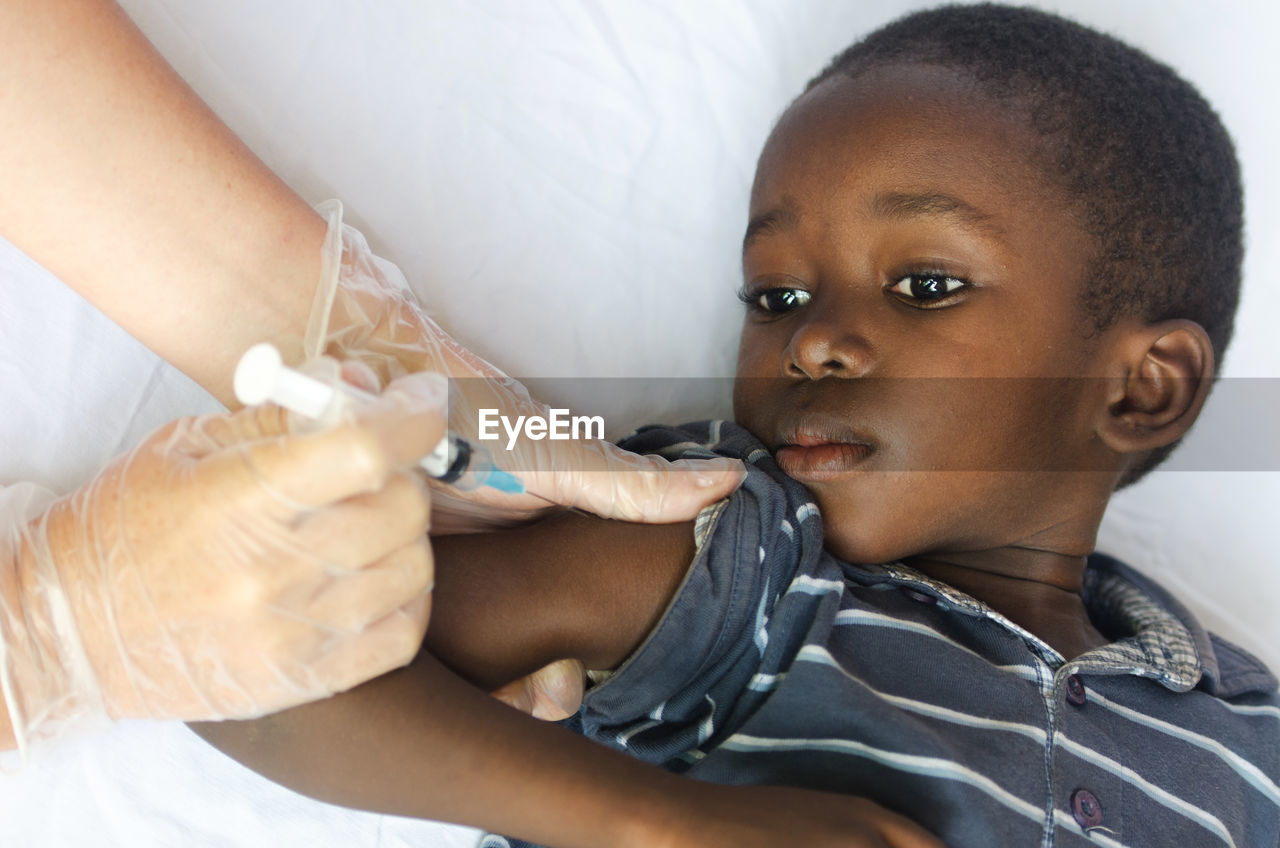 Cropped hands of doctor injecting boy in hospital