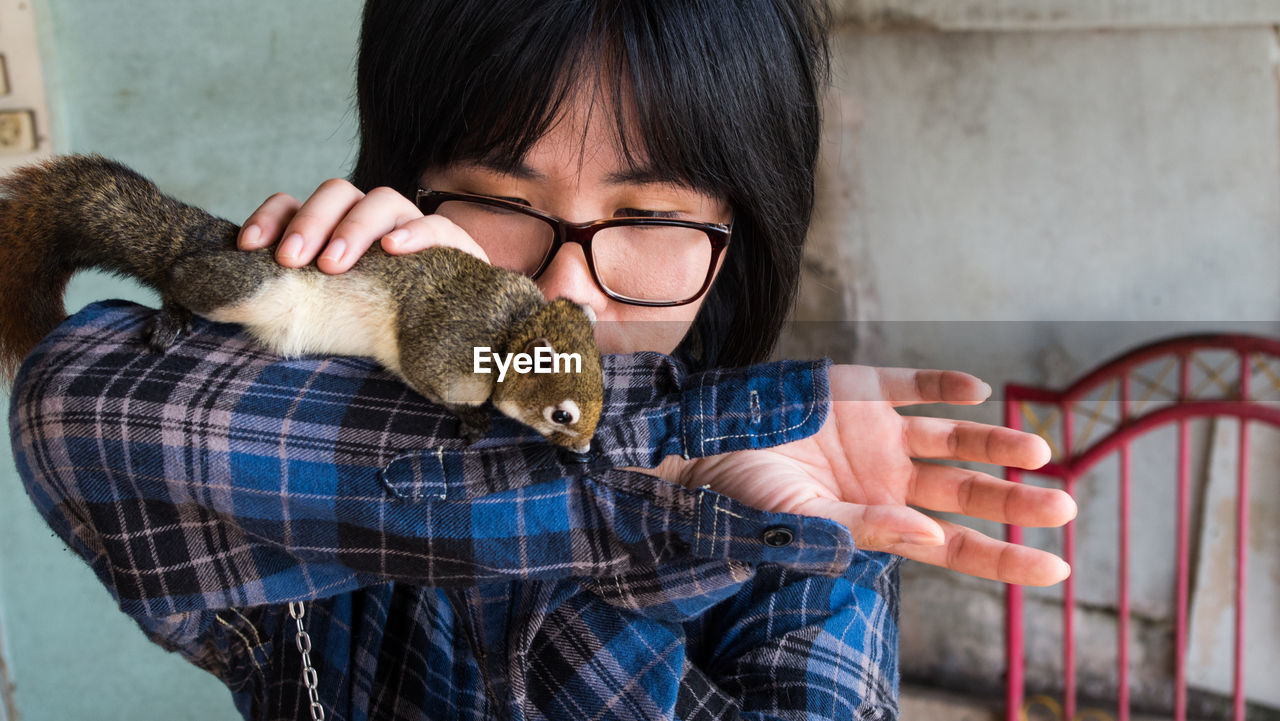 Close-up of boy with squirrel against wall