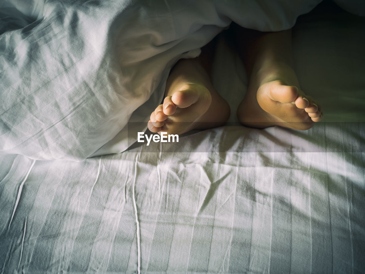 Low section of woman relaxing on bed