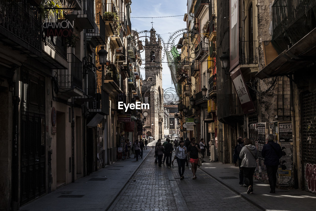 People walking on street amidst buildings in city