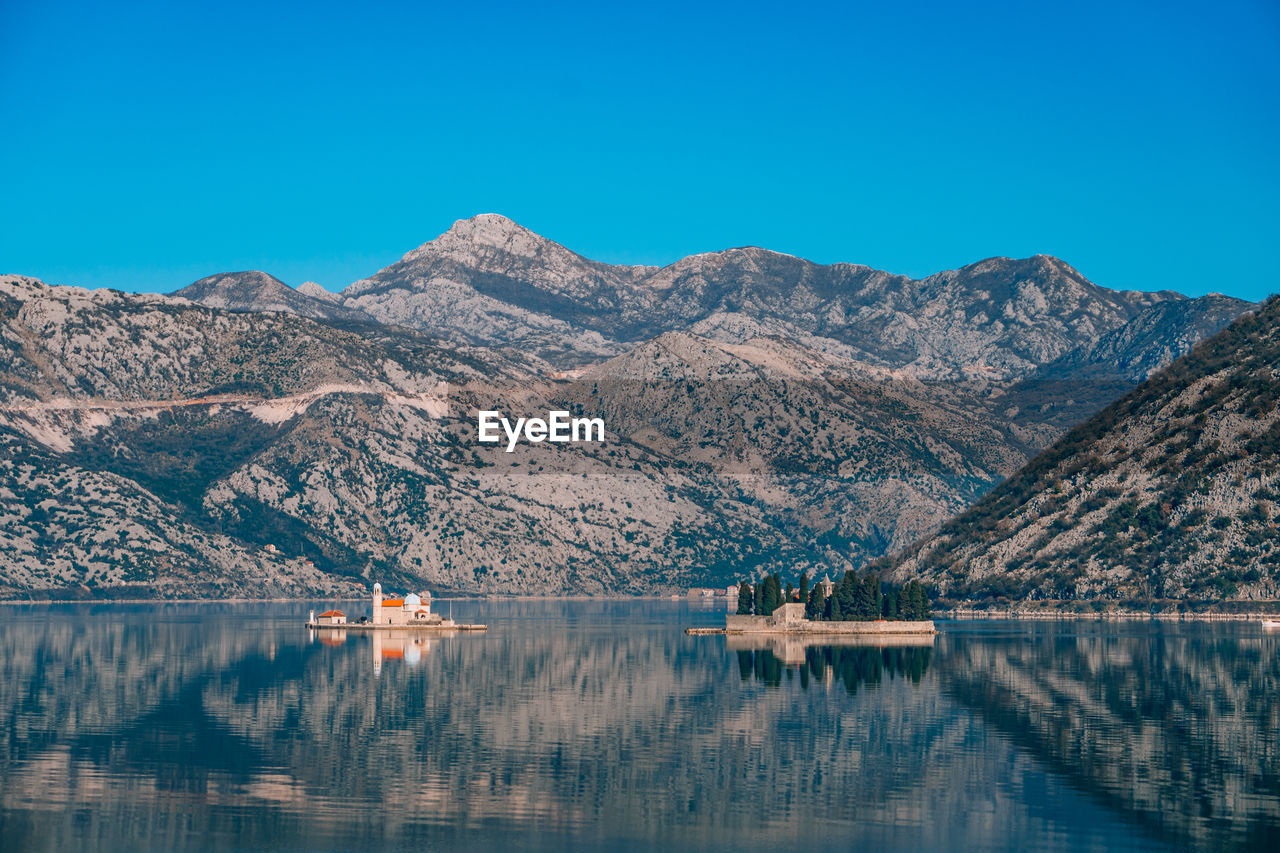 SCENIC VIEW OF LAKE AND MOUNTAINS AGAINST BLUE SKY