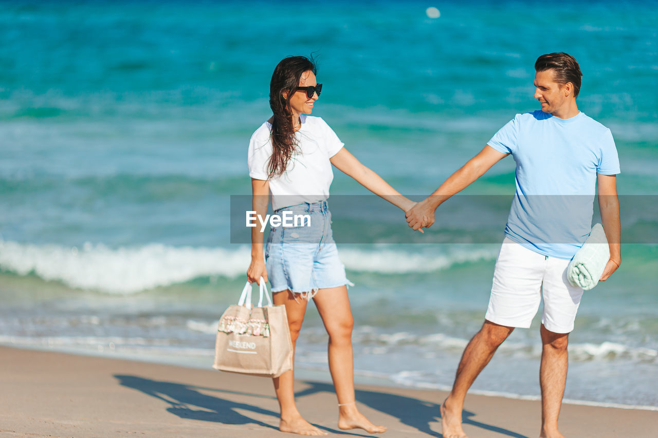 rear view of mother and daughter walking at beach