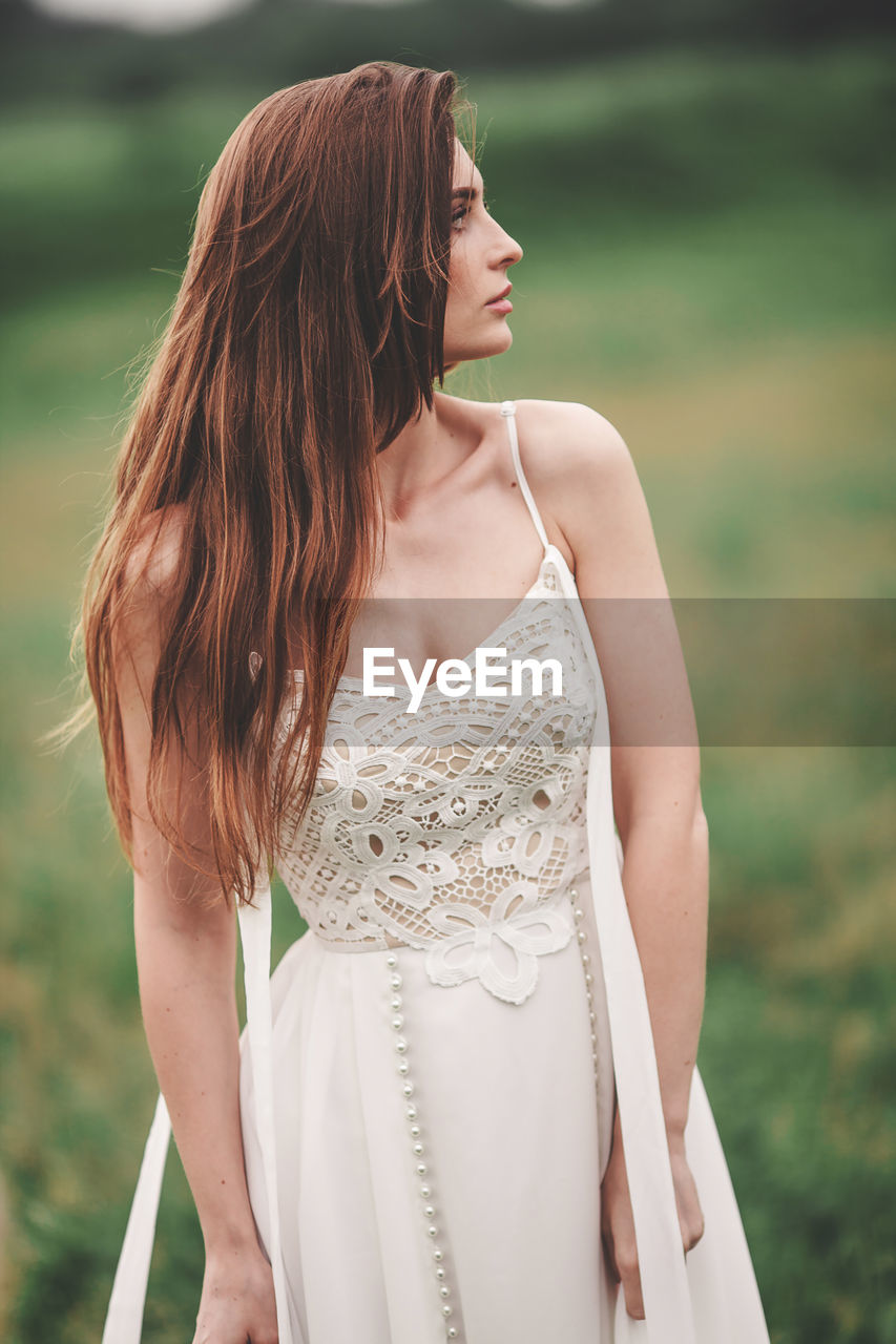 BEAUTIFUL WOMAN LOOKING AWAY WHILE STANDING ON OUTDOORS