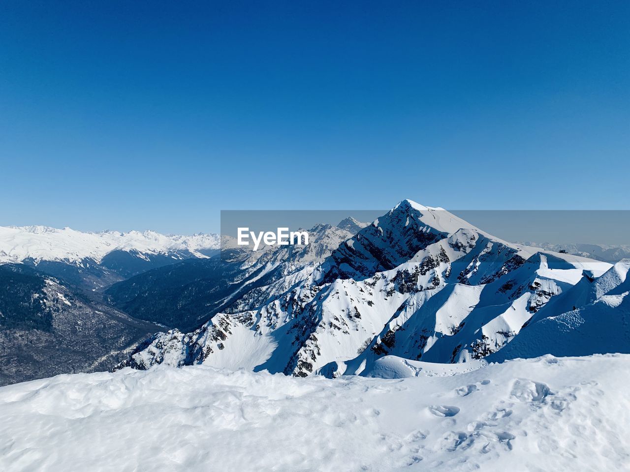 Scenic view of snowcapped mountains against clear blue sky