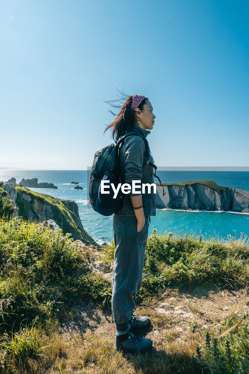 Asian girl hiking along the coast in spring during the sunset