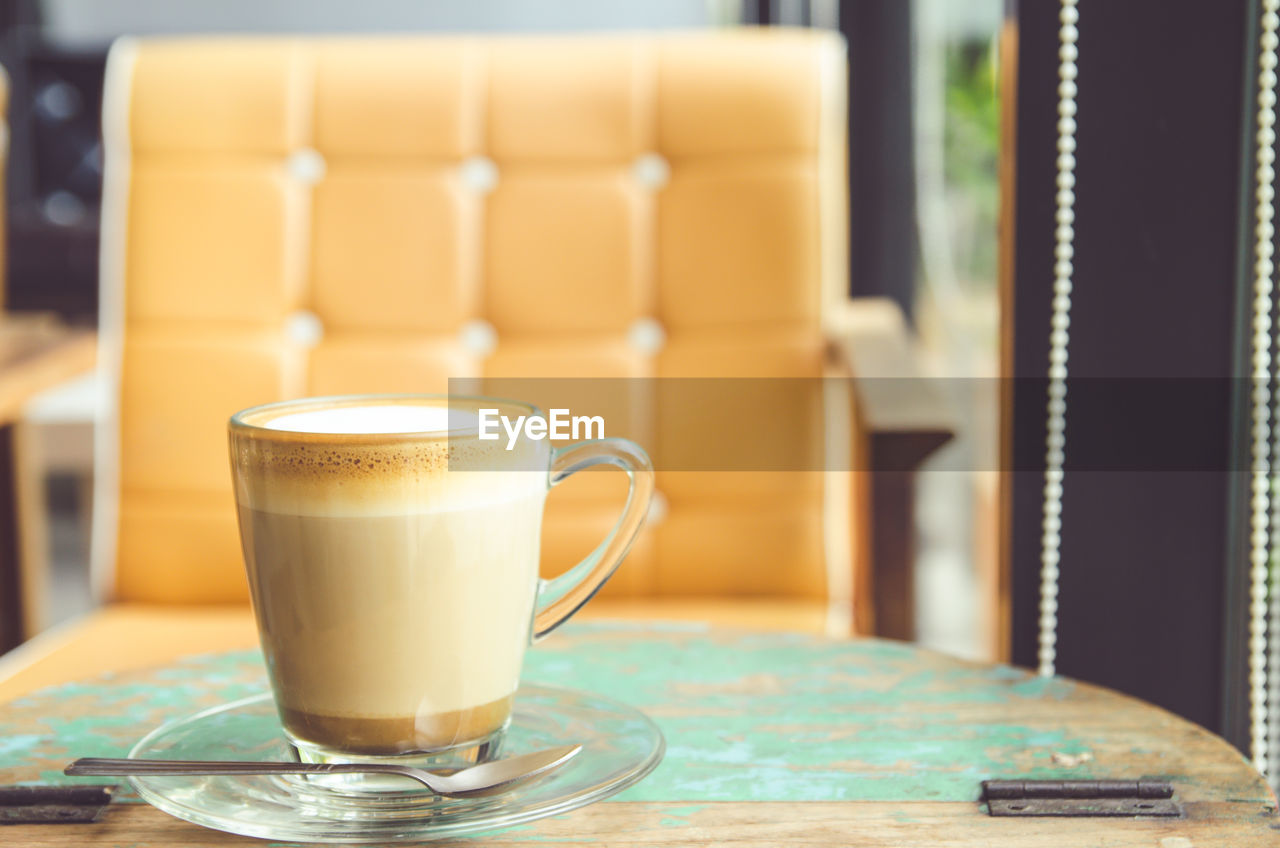 Close-up of cappuccino on table against chair