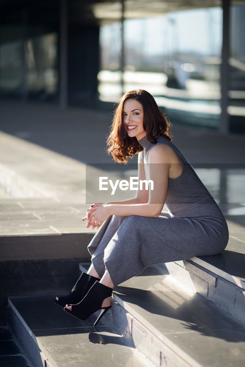 Portrait of smiling young woman sitting on steps