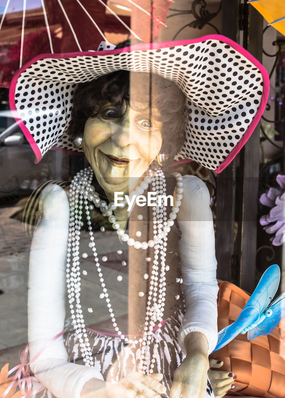 Close-up of mannequin at retail display seen through glass