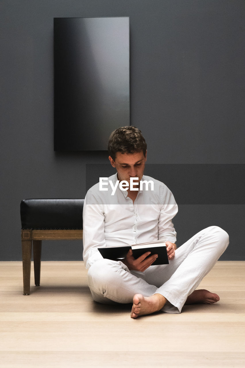 Man reading book while sitting on floor